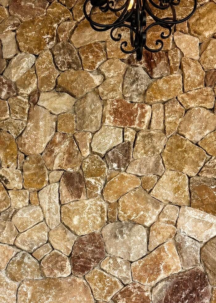 Muro de piedra natural con un candil de herrería